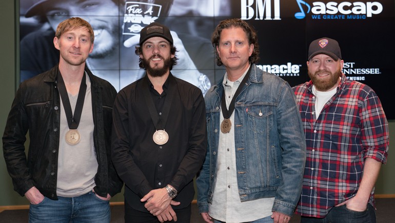Ashley Gorley, Chris Janson, Chris DuBois and producer Brent Anderson gather while celebrating their No. 1 song “Fix A Drink.”