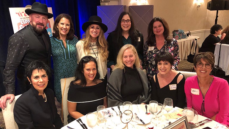 Pictured (L-R) before BMI songwriter Heidi Newfield’s performance at the MIW’s annual Lipstick and Lobster Dinner at the Rosewood Mansion @ Turtle Creek in Dallas are: (standing): guitarist Matt King, The Mesnik Group owner and MIW Spokesperson Denyse Mesnik,  BMI songwriter Heidi Newfield, Geller Media International President Valerie Geller and BMI’s Jessica Frost. (seated): NRG Media President Mary Quass, Ohana Media Group owner Trila Bumstead, Reno Media Group VP/GM Tricia Gallenbeck, Entercom Project Manager Val Blackburn and Presslaff Interactive Revenue President Ruth Presslaff.