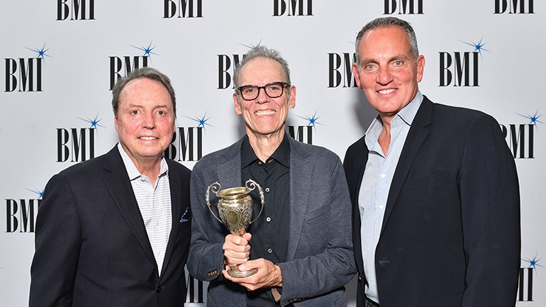 BMI’s Jody Williams, 2019 BMI Troubadour John Hiatt and BMI’s Mike O’Neill pose with the vintage Troubadour trophy.