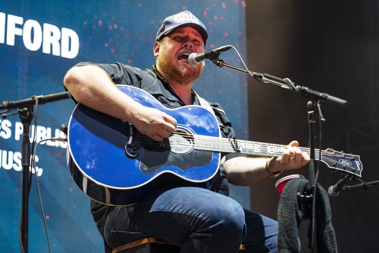 Luke Combs performing live with fans in excitement in 2022