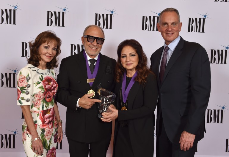  (L) Caroline Beasley, Chairperson, BMI Board of Directors and CEO, Beasley Media Group and (R) Mike O’Neill, President & CEO, BMI honor Emilio and Gloria Estefan at the 72nd Annual BMI/NAB Dinner at the Encore Las Vegas on April 26, 2022.