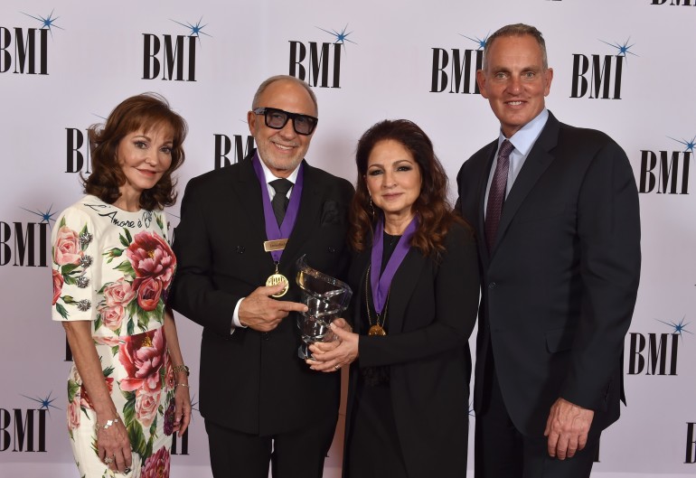 (L) Caroline Beasley, Chairperson, BMI Board of Directors and CEO, Beasley Media Group and (R) Mike O’Neill, President & CEO, BMI honor Emilio and Gloria Estefan at the 72nd Annual BMI/NAB Dinner at the Encore Las Vegas on April 26, 2022.
